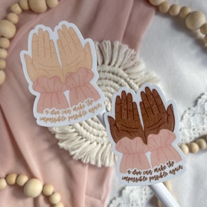 May include: Two stickers with a pair of hands raised in prayer. The text on the stickers reads "a dua can make the impossible possible again".