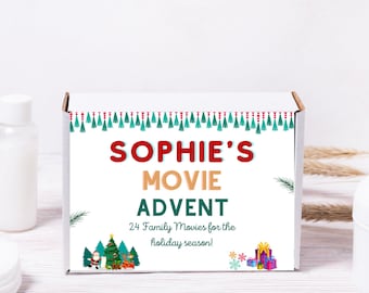 Op de afbeelding: Een witte doos met de tekst "Sophie's Movie Advent" in rode en gouden letters. De doos is versierd met een groen-rode kwastjesrand en een kerstscène met een boom, de kerstman en cadeaus. Bevat 24 familiefilms voor de feestdagen.