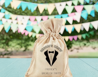 May include: A beige burlap bag with a black graphic of a tuxedo and the text "Groom's Crew" and "Patrick's Bachelor Party".