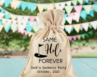 May include: A tan burlap drawstring bag with the text "SAME Hole FOREVER" and a golf club and flag graphic. The bag also has the text "Jack's Bachelor Party October, 2023".