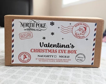 以下が含まれることがあります： 茶色の段ボール製のクリスマスイブボックス。白いラベルには「Valentina's CHRISTMAS EVE BOX」と書かれており、ノースポールエクスプレスのスタンプ、雪の結晶、「DO NOT OPEN BEFORE DECEMBER 24TH」の文字が含まれています。