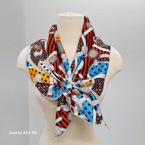 May include: A colorful silk scarf with a geometric pattern in red, blue, white, and black. The scarf features a whimsical design with cartoon-like figures and polka dots.