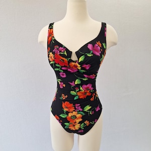 May include: A black one-piece swimsuit with a vibrant floral pattern in shades of red, orange, and pink. The swimsuit features a scoop neckline and a flattering silhouette, perfect for a day at the beach or pool.
