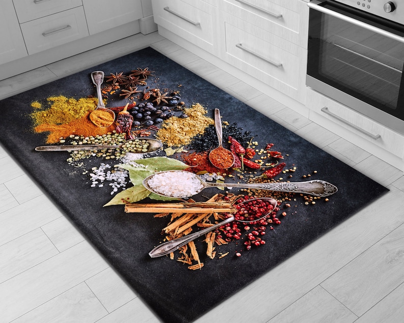 May include: A black kitchen rug with a design of various spices and herbs, including red pepper flakes, cinnamon sticks, and salt. The rug features silver spoons with spices in them, and the design is set against a black background.