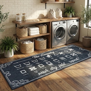 May include: A dark blue laundry room rug with white text and laundry symbols. The rug reads "The Laundry wash, dry, fold... repeat!" and has a decorative border. The rug is on a wooden floor.