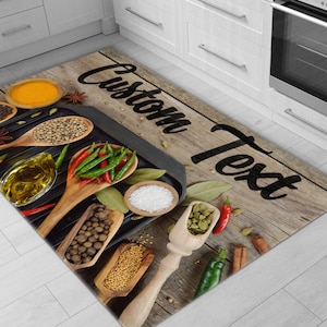 May include: A rectangular kitchen mat with a wooden plank design, featuring the text "Custom Text" in black. The mat showcases various spices, including chili peppers, peppercorns, and herbs, arranged around a black grill pan and wooden spoons.
