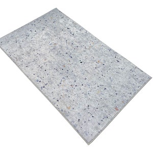 Puede incluir: Una alfombra blanca con un patr&oacute;n moteado de peque&ntilde;as motas grises claras, azules y naranjas.