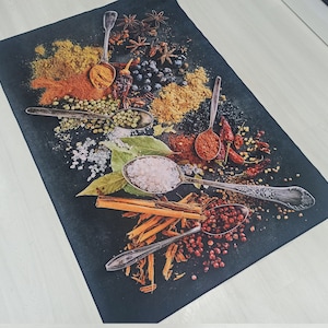 May include: A black background with various spices and herbs, including red pepper flakes, green peppercorns, and cinnamon sticks. There are also several silver spoons filled with different spices, including salt and red pepper.