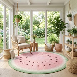 May include: A round rug with a watermelon design. The rug features a pink center with brown seed shapes and a green border. The rug is in a sunroom with a rattan chair, plants, and large windows.