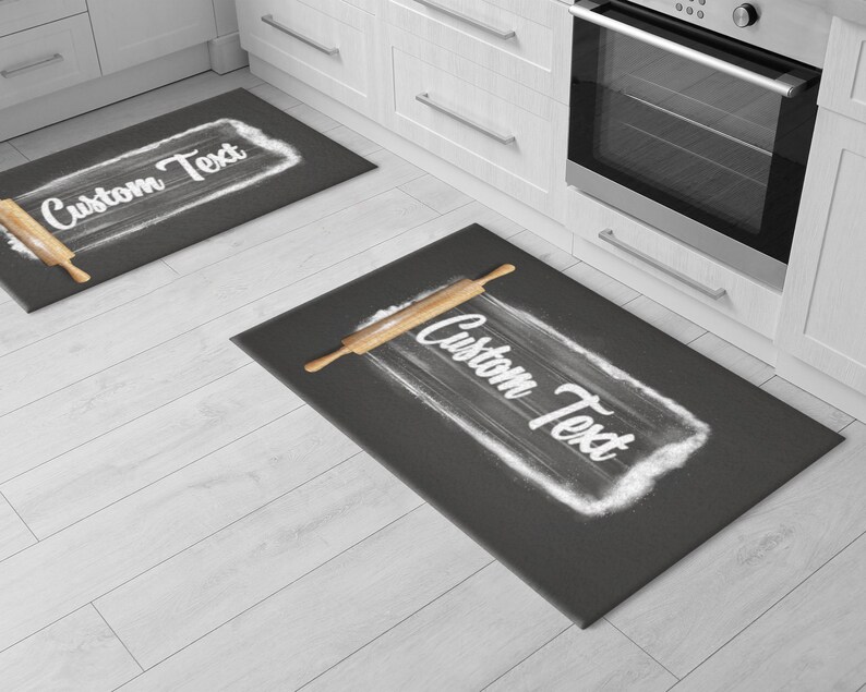 May include: Two gray kitchen rugs with a rolling pin and flour design. The text "Custom Text" is written on each rug.