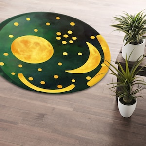 Pode incluir: Um tapete redondo verde e dourado com um design de lua e sol. O tapete tem um fundo verde escuro com pontos dourados e uma lua crescente e um sol cheio.