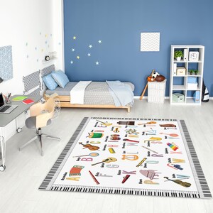 Könnte beinhalten: Ein rechteckiger Teppich mit einem Klaviertastenrand und einer weißen Mitte mit farbenfrohen Illustrationen von Musikinstrumenten und dem Alphabet. Der Teppich befindet sich in einem Kinderzimmer mit Bett, Schreibtisch und Regal.