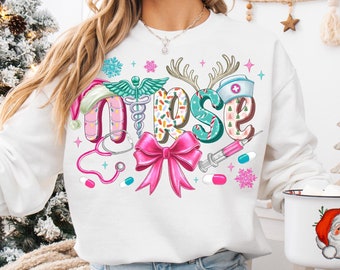 May include: White Christmas themed sweatshirt with the word "Nurse" spelled out in colorful letters with holiday-themed designs. The letters are decorated with candy canes, snowflakes, and a stethoscope.