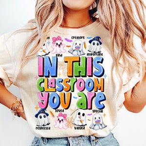 May include: A white t-shirt with a colorful graphic that says "In this classroom you are" surrounded by cute ghost illustrations. Each ghost has a different word on it, such as "creators", "kind", "important", "loved", "respected", "valued", and "special".