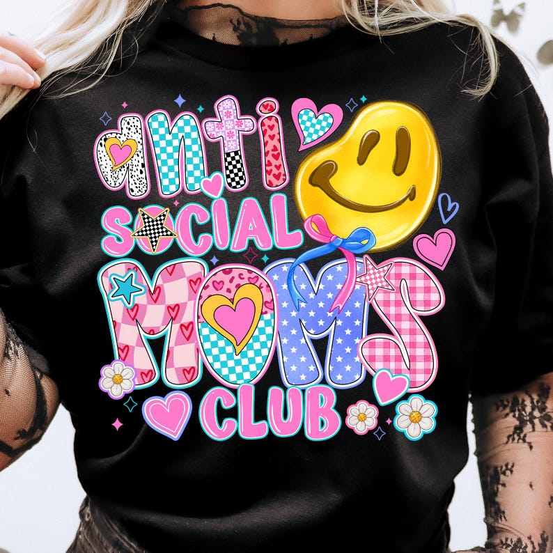 May include: Black t-shirt with a colorful graphic design that says "Anti Social Moms Club". The graphic features a smiley face, hearts, stars, and checkered patterns.