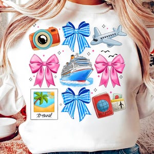 Puede incluir: Sudadera blanca con un tema de viaje que presenta un crucero, un avi&oacute;n, una c&aacute;mara, un pasaporte, una palmera y lazos en rosa y azul.