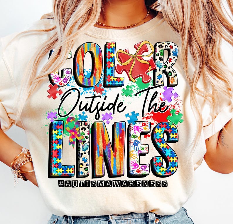 May include: A white t-shirt with a colorful graphic design that says "Color Outside The Lines" with puzzle pieces and the hashtag #autismawareness.