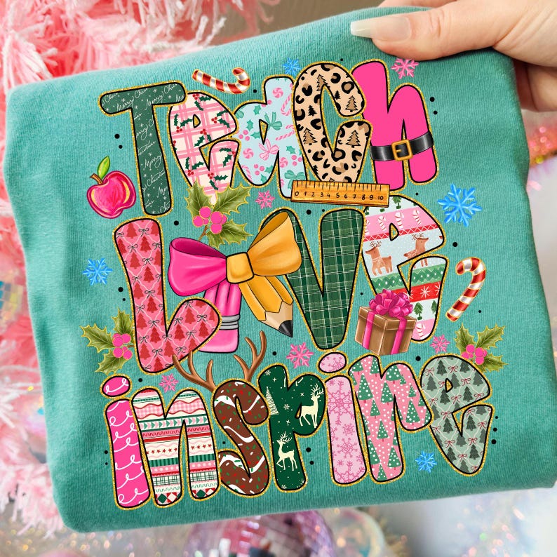 Pu&ograve; includere: T-shirt turchese con le parole "Teach Love Inspire" in un design colorato e fantasia. Le lettere sono decorate con vari elementi festivi e scolastici, tra cui mele, matite e fiocchi di neve. Una mano tiene la maglietta.
