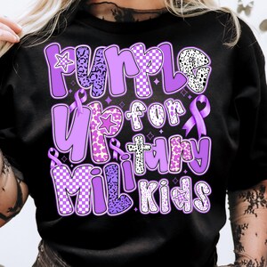 May include: Purple Up for Military Kids t-shirt with a purple, white and black chequered pattern, leopard print and flowers. The shirt has a purple ribbon and stars.