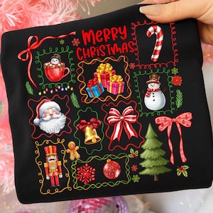 Pu&ograve; includere: Felpa nera a tema natalizio con illustrazioni colorate di Babbo Natale, un pupazzo di neve, regali e un albero di Natale. Le parole "Merry Christmas" sono scritte in rosso. C'&egrave; anche un bastoncino di zucchero.