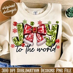 May include: A white sweatshirt with a green and red "Joy to the World" design. The word "Joy" is made of green and red squares with a red bow and white trim. The design is surrounded by snowflakes and ornaments.