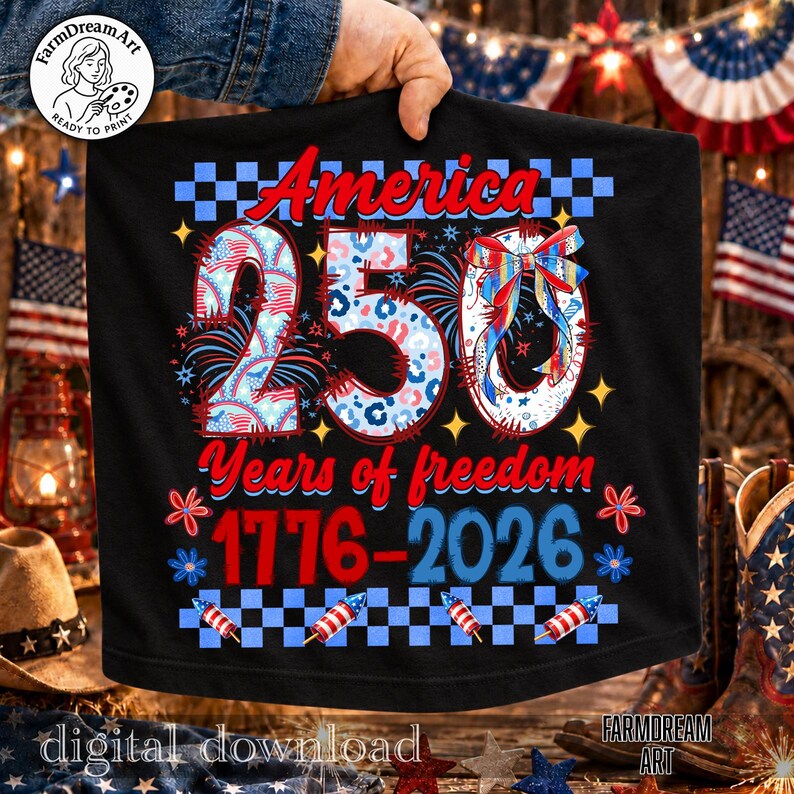 May include: Black t-shirt with a patriotic design celebrating America's 250th anniversary. The design includes the word "America", the number "250", and the years "1776-2026" in red, white, and blue. Fireworks and stars complete the design.