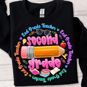 May include: Black sweatshirt with a colorful graphic design for a 2nd-grade teacher. The design includes a large pencil, the words "Second Grade", and other school-related icons like glasses, an apple, and books.