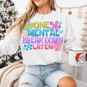 May include: White sweatshirt with a colorful graphic that says "One Mental Breakdown Later" with a flower design.