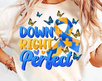 May include: A white t-shirt with a blue and yellow ribbon made of puzzle pieces. The ribbon is surrounded by butterflies. The text "Down Right Perfect" is written in blue and yellow letters.