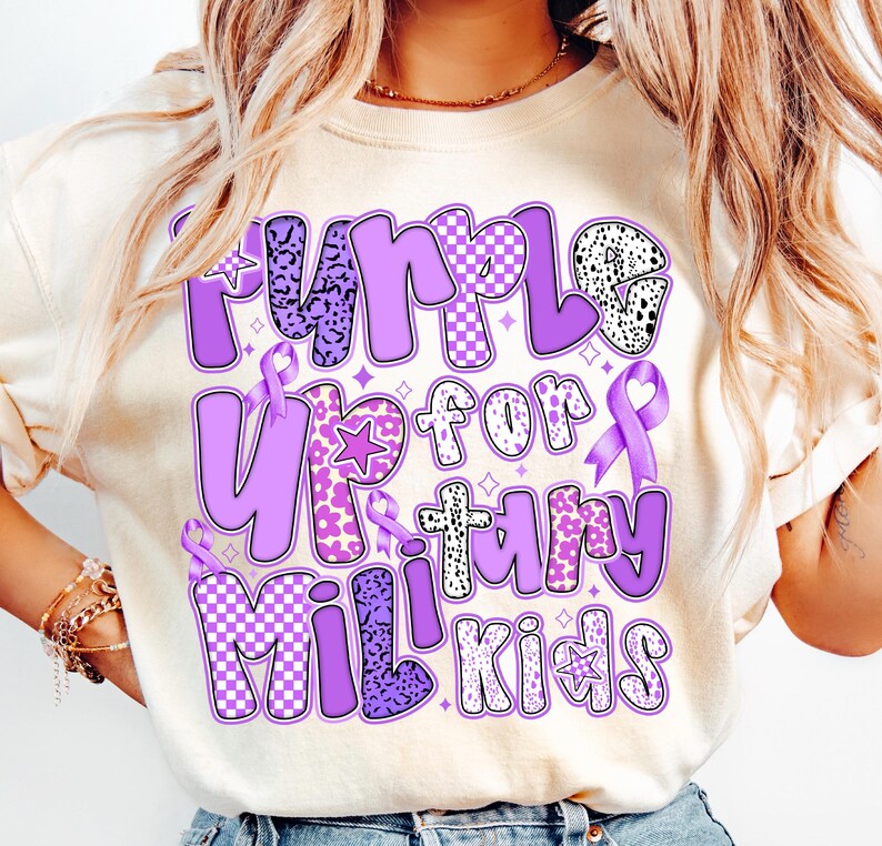 May include: A purple t-shirt with the text "Purple Up for Military Kids" in a colourful, patterned font. The text is surrounded by purple ribbons and stars.