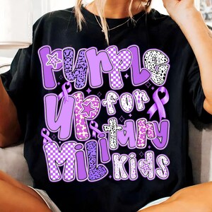 May include: Purple t-shirt with the text "Purple Up for Military Kids" in a purple, checkered, and floral design. The text is surrounded by purple ribbons.