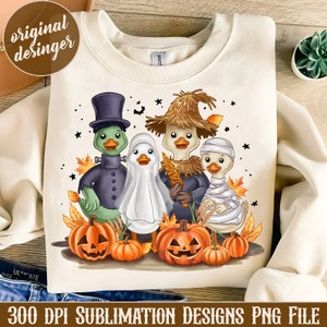 Pode incluir: Camisola creme com um design temático de Halloween. O design inclui quatro patos vestidos como Frankenstein, fantasma, espantalho e múmia, juntamente com abóboras e folhas de outono. O texto "300 DPI SUBLIMATION DESIGNS PNG FILE" está na parte inferior.