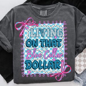 Pu&ograve; includere: Felpa girocollo grigio scuro con la scritta "LIVING ON THAT Blue Collar DOLLAR" in un design blu e rosa. Il design include uno sfondo a scacchi, fiocchi e stelle.