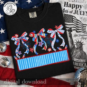 May include: Black t-shirt featuring a patriotic design with three decorative bows in red, white, and blue, along with fireworks and floral accents. The shirt has a blue striped banner and the text "Happy 4th of July!" is visible in the background.