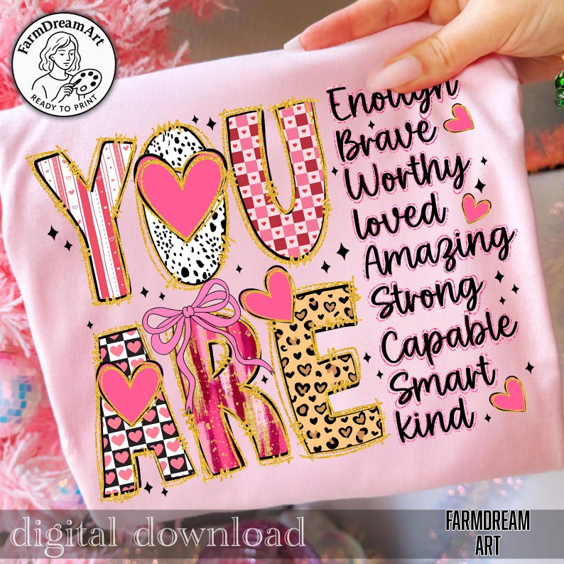 May include: A pink t-shirt with the words "YOU ARE" in a decorative font, featuring hearts and a bow. The words "Enough, Brave, Worthy, Loved, Amazing, Strong, Capable, Smart, Kind" are also printed on the shirt. The words "digital download" are at the bottom.