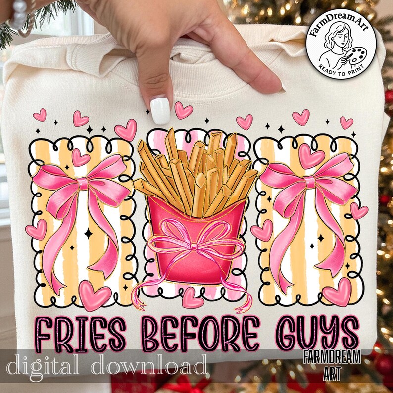 Op de afbeelding: Cr&egrave;mekleurige sweatshirt met een grafisch ontwerp. Het heeft een roze bakje friet, roze strikken en harten. De tekst "FRIES BEFORE GUYS" staat onder de afbeelding. De woorden "digital download" en een logo zijn ook zichtbaar.