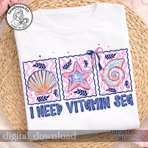 Pu&ograve; includere: T-shirt bianca con una grafica colorata di conchiglie, una stella marina e una conchiglia di nautilus, ciascuna in una cornice rosa e bianca. Il testo "I NEED VITAMIN SEA" &egrave; stampato in blu. La maglietta ha uno scollo tondo.