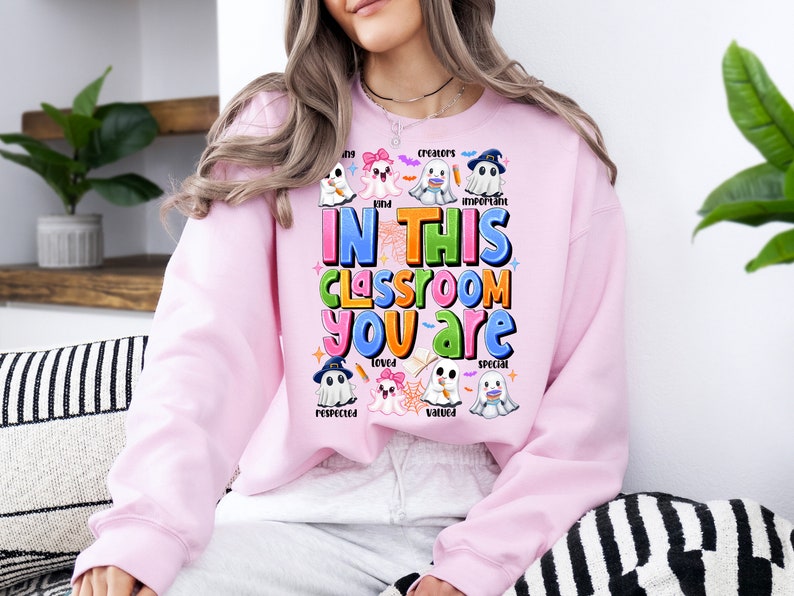 May include: Pink sweatshirt with a ghost theme. The text reads "In this classroom you are" with words like "kind", "creators", "important", "loved", "respected", "valued", and "special" around the ghosts.