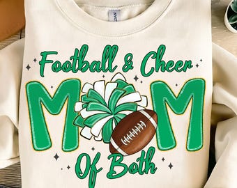 Op de afbeelding: Crèmekleurige sweatshirt met de tekst "Football & Cheer Mom of Both" in het groen. Het ontwerp bevat een groen-witte pompon en een bruine voetbal. De sweatshirt is een casual kledingstuk.