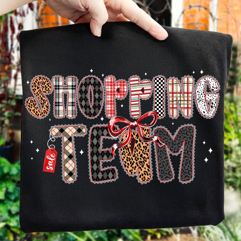 Peut inclure: Sweat-shirt noir avec l'inscription "SHOPPING TEAM" dans un motif patchwork. Les lettres sont d&eacute;cor&eacute;es d'imprim&eacute;s l&eacute;opard, &eacute;cossais et &agrave; pois. Un n&oelig;ud rouge et une &eacute;tiquette "soldes" ajoutent des d&eacute;tails festifs.