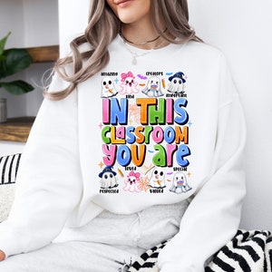 May include: White sweatshirt with a colorful graphic of ghosts and the text "In this classroom you are amazing, kind, creators, important, loved, valued, special, respected".