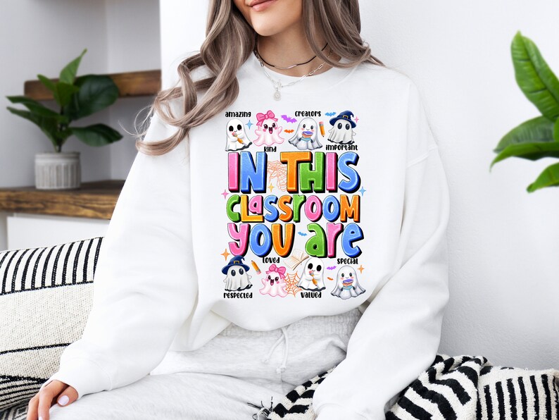 May include: White sweatshirt with a colorful graphic of ghosts and the text "In this classroom you are amazing, kind, creators, important, loved, valued, special, respected".