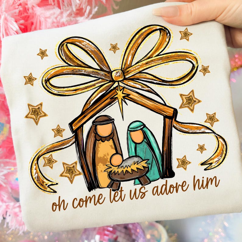 Pu&ograve; includere: T-shirt color crema con una grafica del presepe con Giuseppe, Maria e Ges&ugrave; bambino in una mangiatoia. Il design include un fiocco dorato, stelle e la scritta "oh come let us adore him."