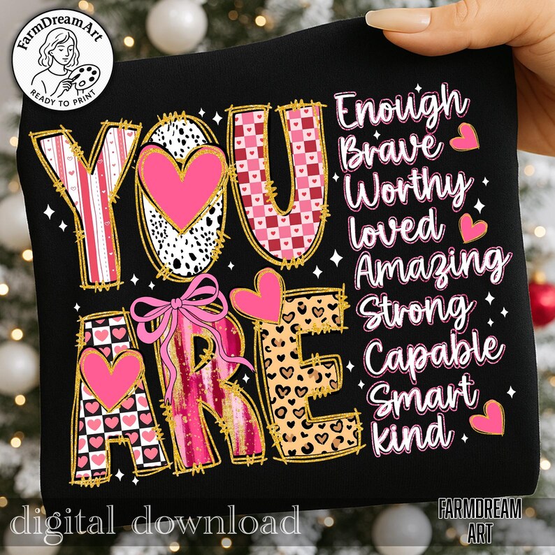 May include: Black graphic design with the words "YOU ARE" in a variety of patterns, including pink hearts, leopard print, and checkered designs. The words "Enough, Brave, Worthy, Loved, Amazing, Strong, Capable, Smart, Kind" are also displayed.