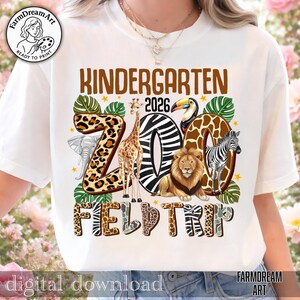 May include: White t-shirt with a colorful "Kindergarten 2026 Zoo Field Trip" design. The design features a giraffe, lion, zebra, toucan, and elephant. The word "ZOO" is in a zebra print. The shirt has a round neckline and short sleeves.