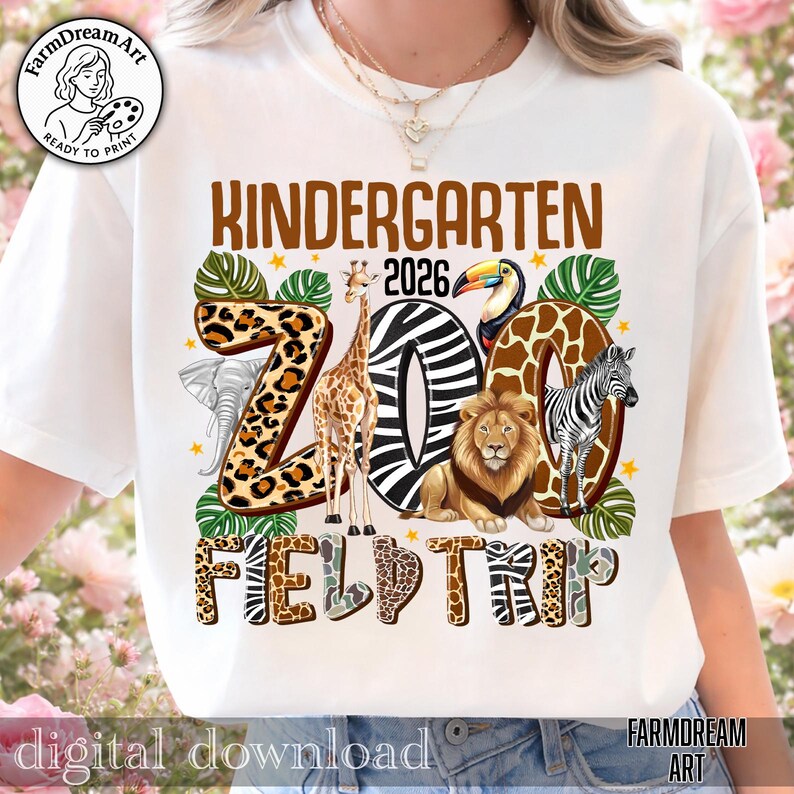 May include: White t-shirt with a colorful "Kindergarten 2026 Zoo Field Trip" design. The design features a giraffe, lion, zebra, toucan, and elephant. The word "ZOO" is in a zebra print. The shirt has a round neckline and short sleeves.