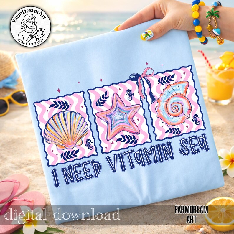 Pu&ograve; includere: Maglietta azzurra con un design grafico che presenta tre illustrazioni di conchiglie e la scritta "I NEED VITAMIN SEA". Il design include una conchiglia, una stella marina e una conchiglia a spirale, il tutto in colori pastello. Sono visibili anche le parole "download digitale".