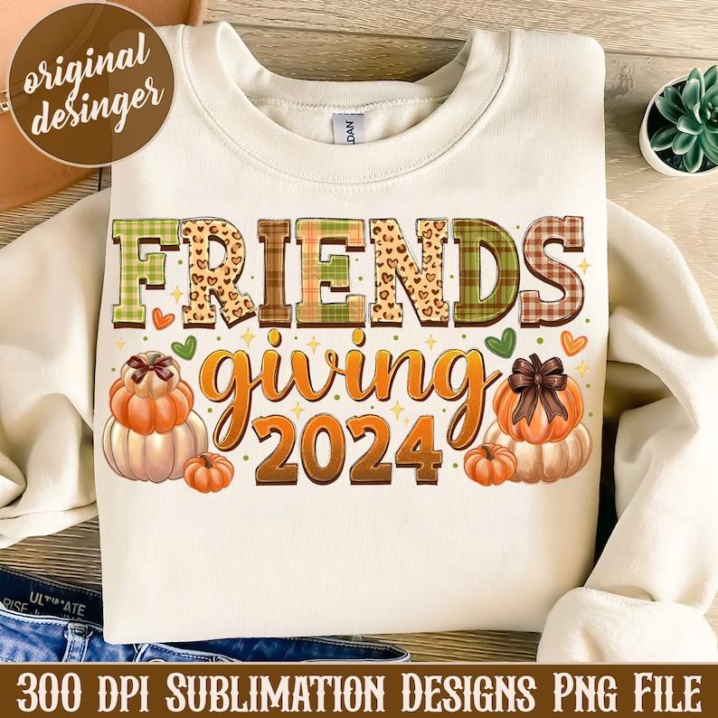 May include: A white sweatshirt featuring the text "FRIENDSgiving 2024" in colourful patchwork letters. The letters are decorated with hearts, stars, and a leopard print. The design also includes three pumpkins with bows.