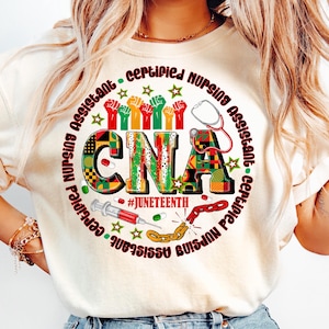 May include: Cream-colored t-shirt with a circular graphic featuring the text "CNA" in bold letters, with the words "Certified Nursing Assistant" circling the design. The graphic includes a stethoscope, syringe, and the hashtag #Juneteenth.