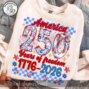 May include: White sweatshirt with a patriotic design celebrating America's 250th anniversary. The design features the word "America" in red script, the number "250" with a mix of patterns, and the text "Years of freedom 1776-2026".